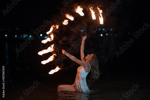 Caucasian woman dancing with fire in the water. Fire show at sea. Acrobatics on the beach. Yoga and relaxation at sunset. Spectacular circus performance. model body. High quality FullHD footage. 