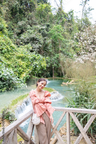 Young Asian woman standing on the wooden walkway in the Kuang Si Waterfall Popular attractions of Lung Prabang, Laos photo