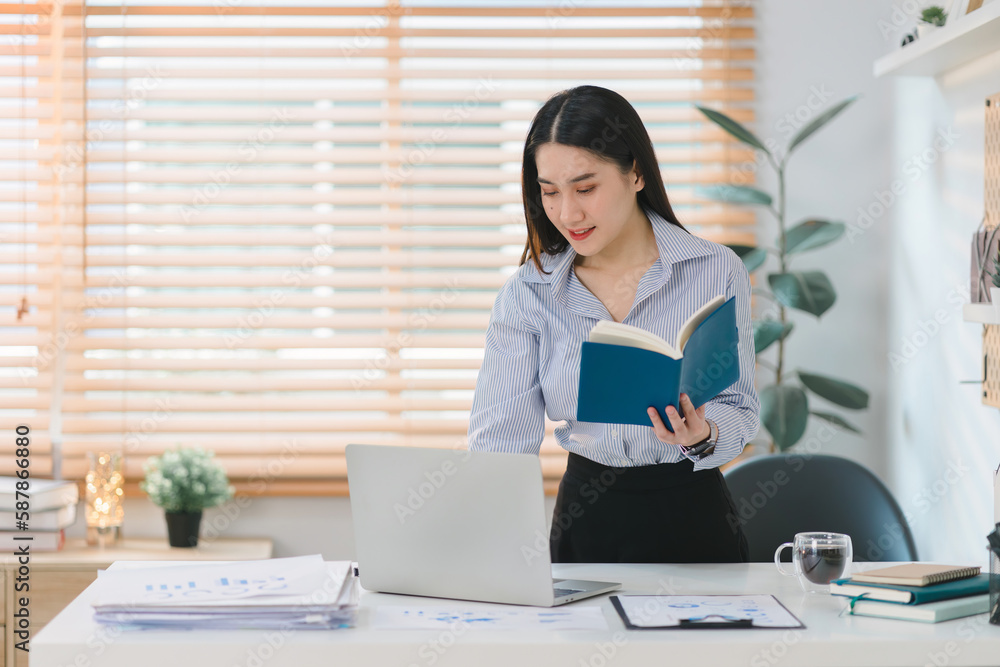 A millennial businesswoman from a startup is working with financial report paperwork, depicting the concept of financial advising, teamwork, and accounting. A millennial businesswoman from a startup is working with financial report paperwork, depicting the concept of financial advising, teamwork, and accounting.