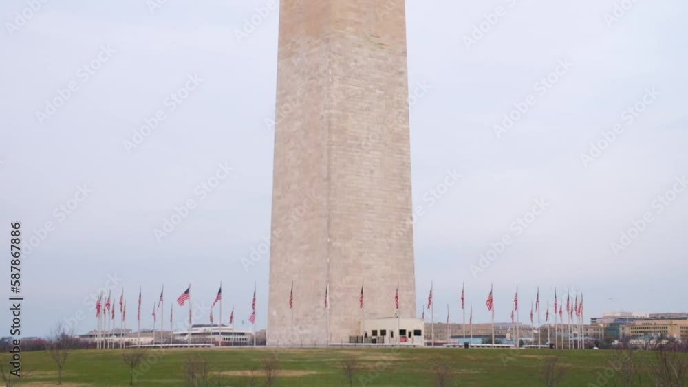 Tilt Up Shot Of United States Flags Around Obelisk Shaped Building Against Sky - Washington, District of Columbia Tilt Up Shot Of United States Flags Around Obelisk Shaped Building Against Sky - Washington, District of Columbia