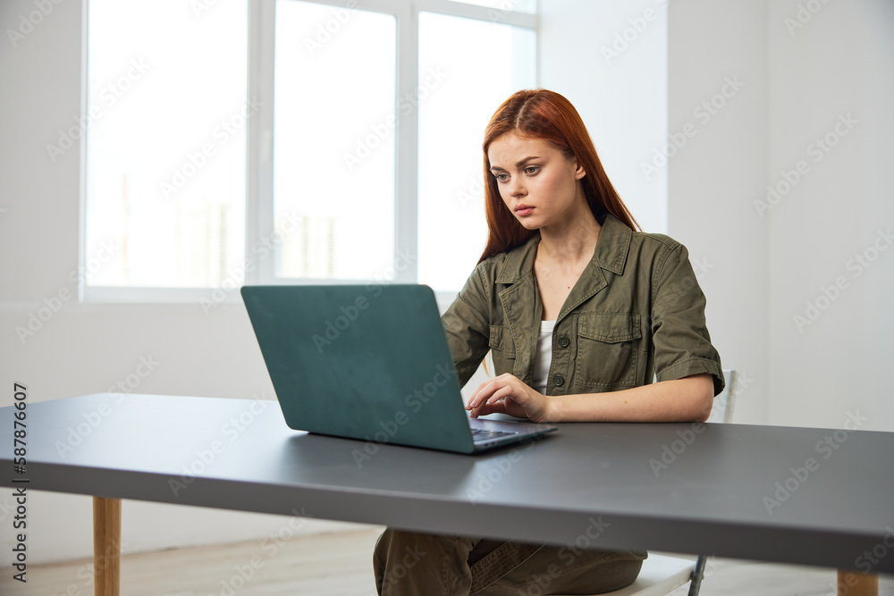 portrait of a red-haired woman in the office sitting thoughtfully at a laptop portrait of a red-haired woman in the office sitting thoughtfully at a laptop