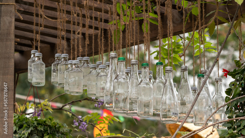 there are many glass bottles hanging as decorations under the eaves in the garden photo