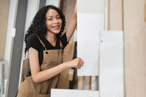 Happy teenager carpenter African American woman working with wood sheet at wood factory 