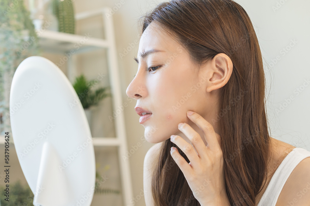 Dermatology, puberty asian young woman, girl looking into mirror, allergy presenting an allergic reaction from cosmetic, red spot or rash on face. Beauty care from skin problem by medical treatment. Dermatology, puberty asian young woman, girl looking into mirror, allergy presenting an allergic reaction from cosmetic, red spot or rash on face. Beauty care from skin problem by medical treatment.