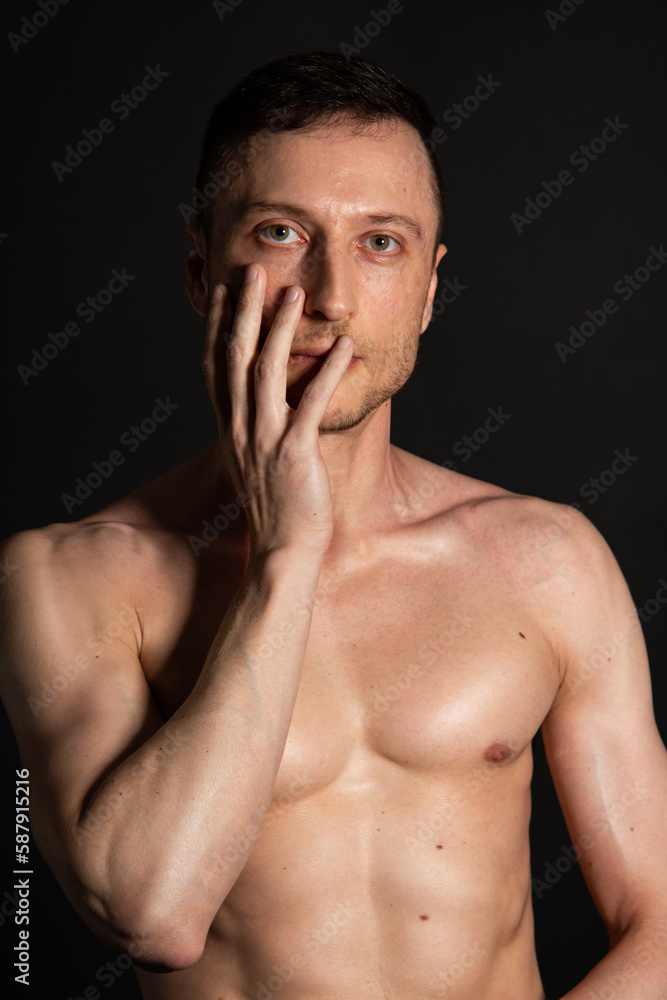 Adult attractive man with a beautiful body posing in the studio. Black background. Adult attractive man with a beautiful body posing in the studio. Black background.