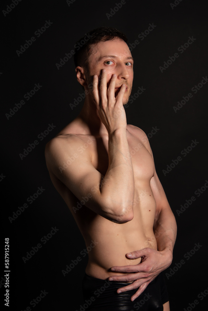 Adult attractive man with a beautiful body posing in the studio. Black background. Adult attractive man with a beautiful body posing in the studio. Black background.