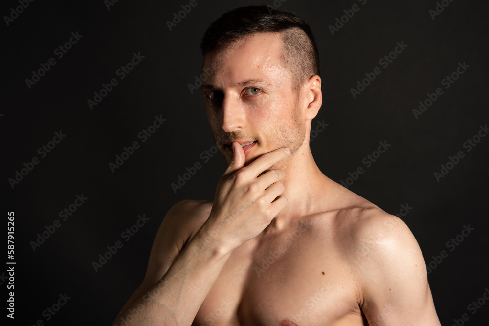 Adult attractive man with a beautiful body posing in the studio. Black background. Adult attractive man with a beautiful body posing in the studio. Black background.