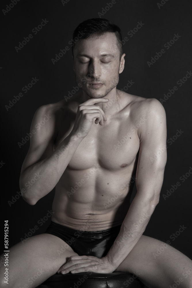 Adult attractive man with a beautiful body posing in the studio. Black background. Adult attractive man with a beautiful body posing in the studio. Black background.