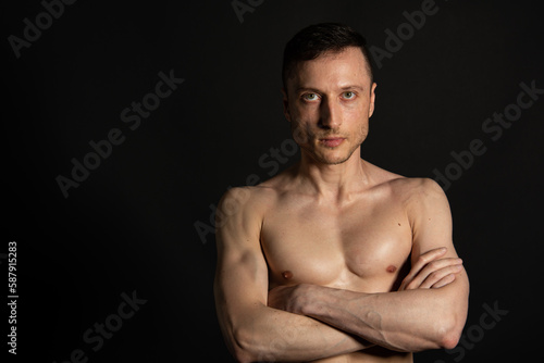 Adult attractive man with a beautiful body posing in the studio. Black background.