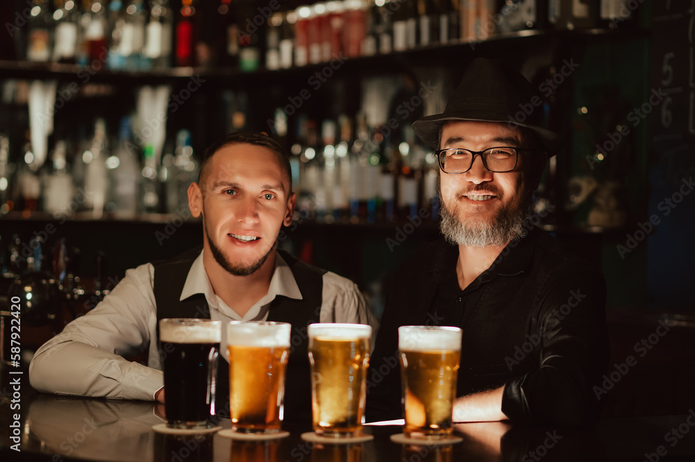 two happy bartenders at bar counter with glasses of beer in pub