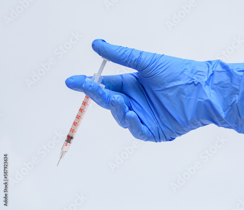 Szczepionka trzymana w dłoni w niebieskiej rękawiczce na białym tle