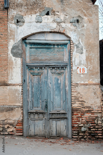 Closed wooden old door and shabby brick wall at abandoned house