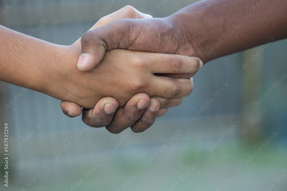 Tow friends are handshipping, one with white hands and the other with black hands . Tow friends are handshipping, one with white hands and the other with black hands .