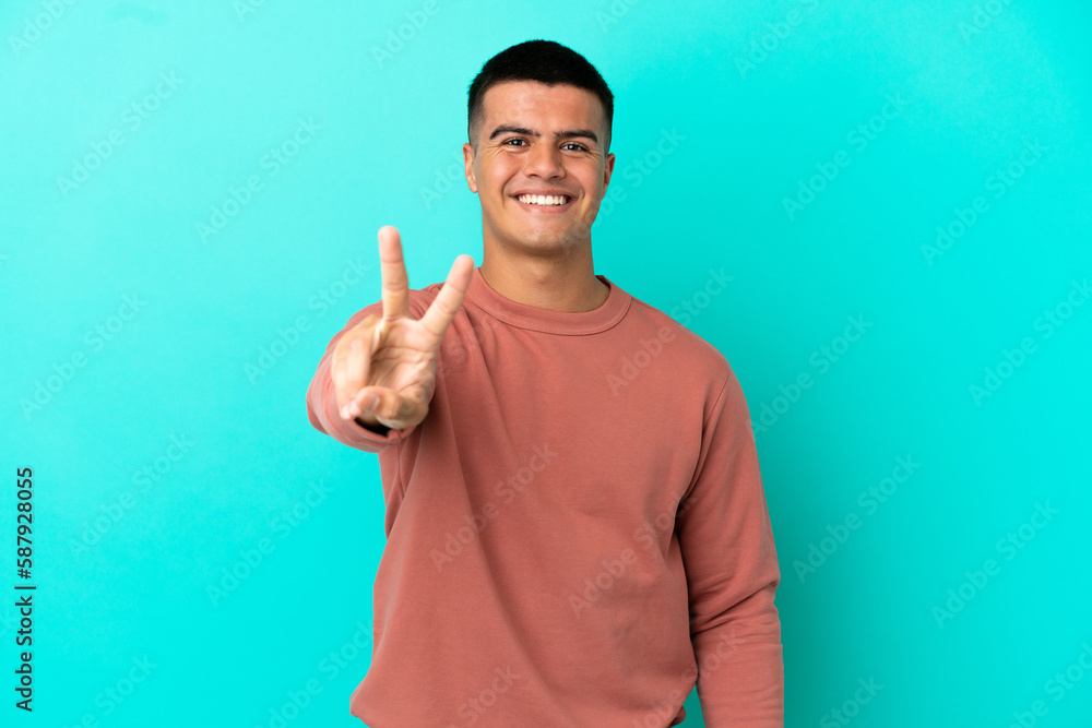 Young handsome man over isolated blue background smiling and showing victory sign Young handsome man over isolated blue background smiling and showing victory sign