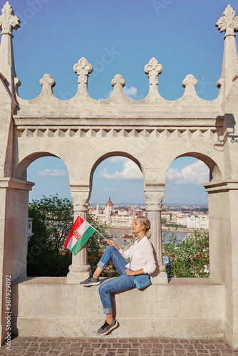 Vacation in Budapest. Young traveling woman with national hungarian flag enjoying city view. © luengo_ua