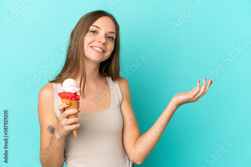 Young Lithuanian woman with cornet ice cream isolated on blue background extending hands to the side for inviting to come