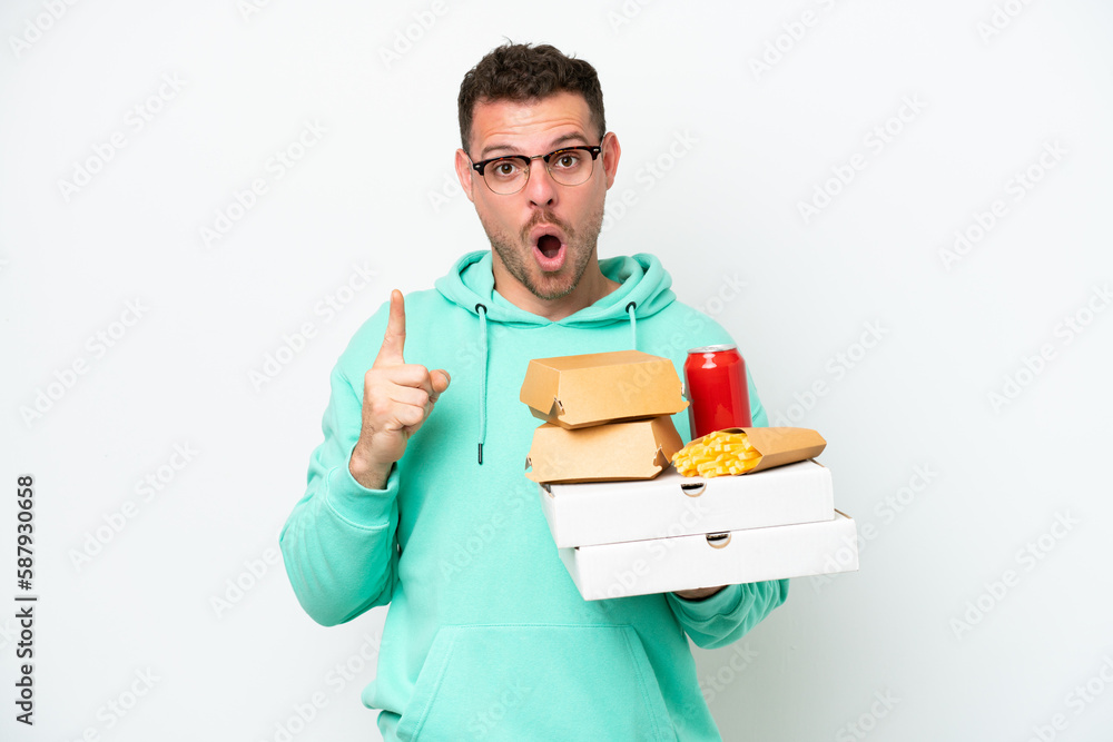 Young caucasian man holding fast food isolated on white background intending to realizes the solution while lifting a finger up Young caucasian man holding fast food isolated on white background intending to realizes the solution while lifting a finger up