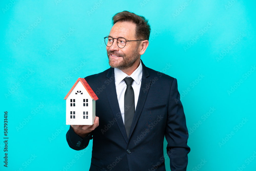 Real estate middle age agent man isolated on blue background looking to the side and smiling Real estate middle age agent man isolated on blue background looking to the side and smiling