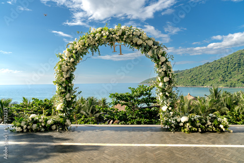 View of decorated wedding chairs with fabric and flowers near the beach