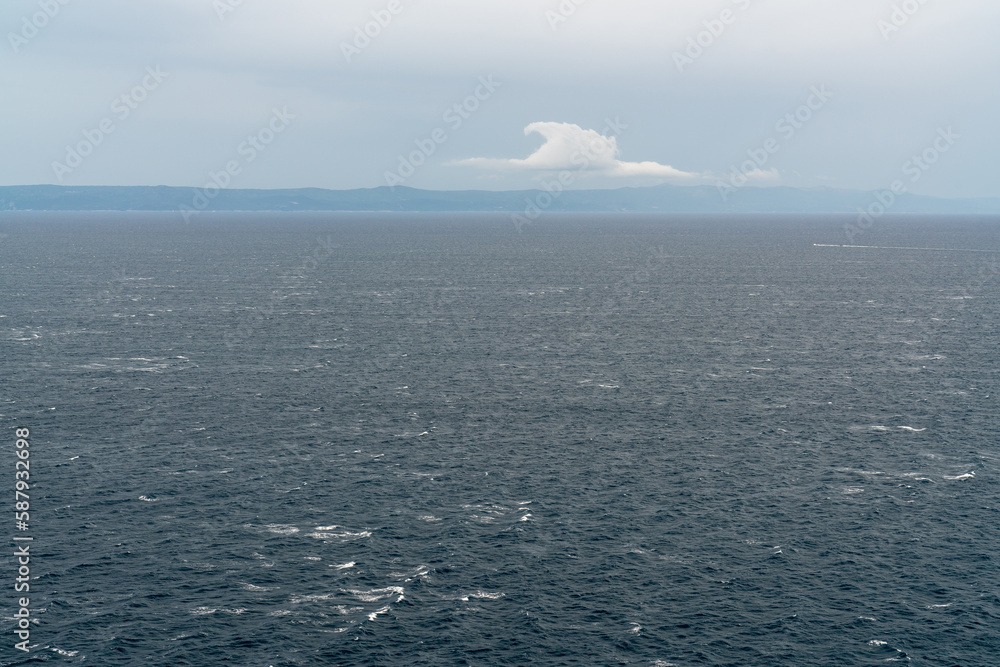 Seascape. Blue sea. Mountain landscape on the horizon. There is one beautiful cloud in the sky Seascape. Blue sea. Mountain landscape on the horizon. There is one beautiful cloud in the sky