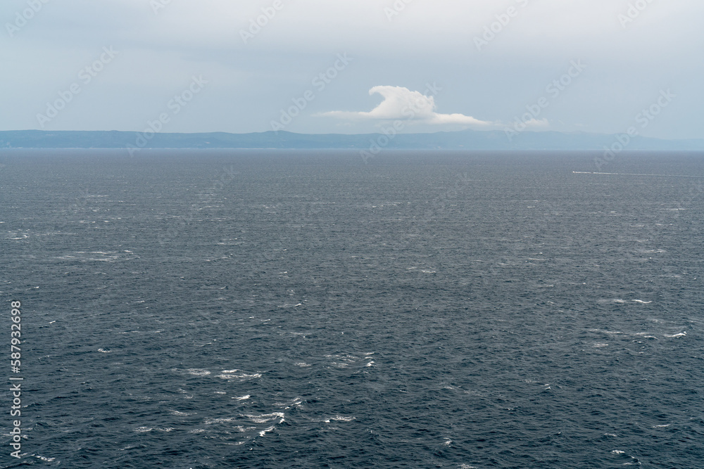 Seascape. Blue sea. Mountain landscape on the horizon. There is one beautiful cloud in the sky