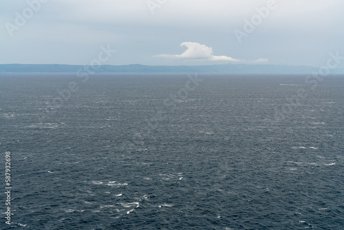Seascape. Blue sea. Mountain landscape on the horizon. There is one beautiful cloud in the sky