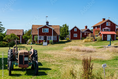 An old tractor, red houses and a communal hand water pump in a small village on the island of Harstena in the Gryt archipelago in the Baltic Sea photo