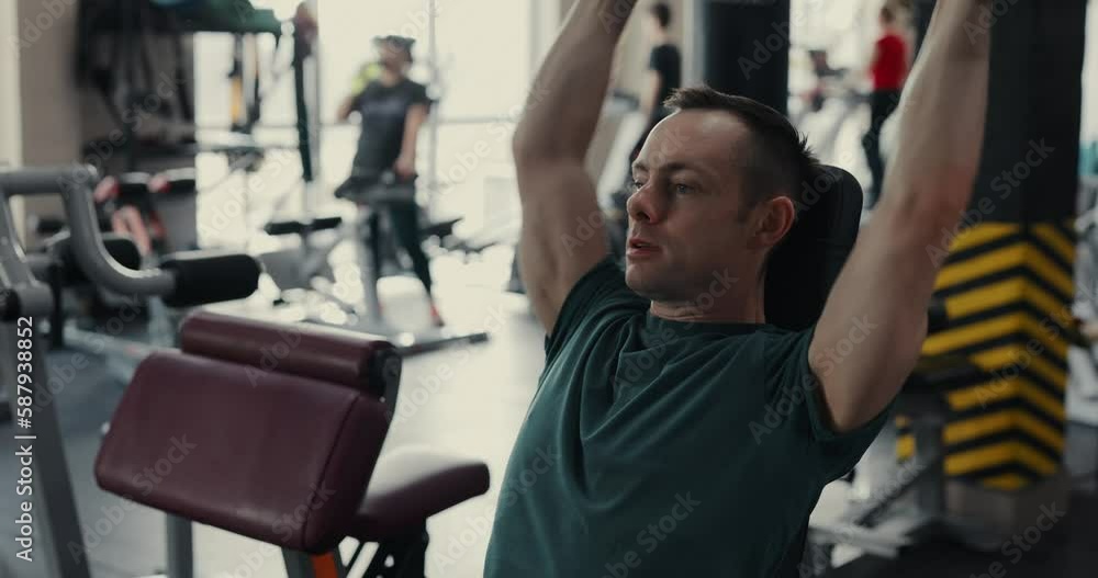 Strong man lifting dumbbells at the gym pumping deltoid muscles Strong man lifting dumbbells at the gym pumping deltoid muscles
