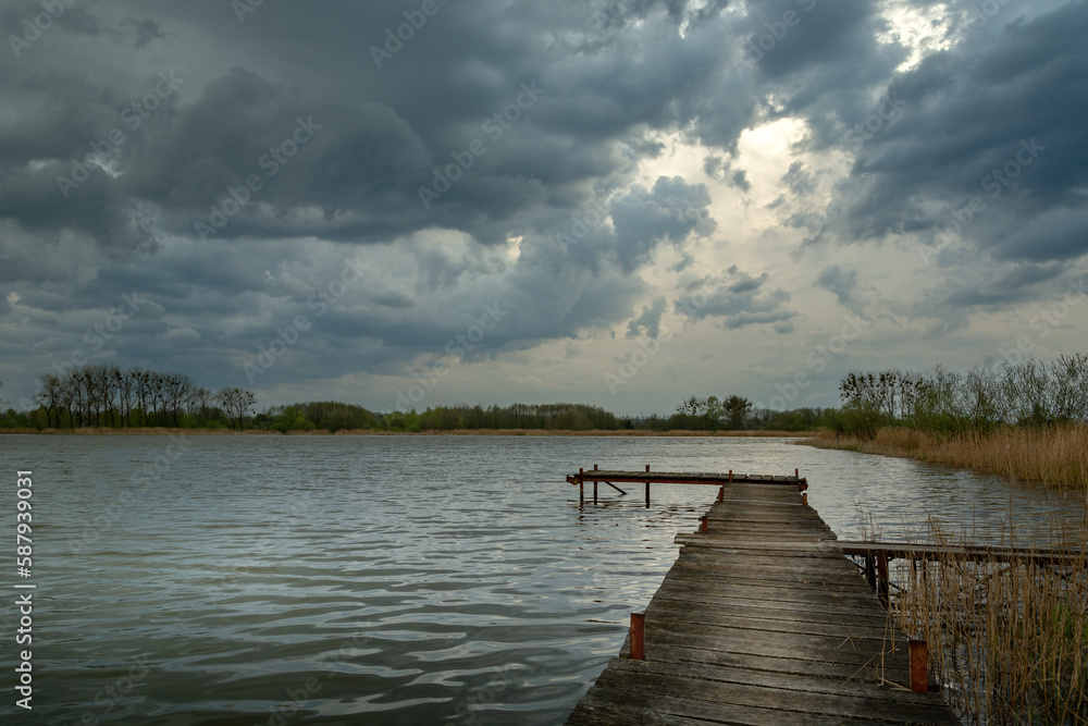 Cloudy stormy sky over a lake with a pier