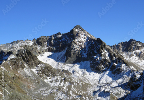 First snow on the rocky mountain peak Piz Sarsura Pitschen (3132 m) in the Albula Alps and above the alpine valley Val Grialetsch, Zernez - Canton of Grisons, Switzerland (Kanton Graubünden, Schweiz)
