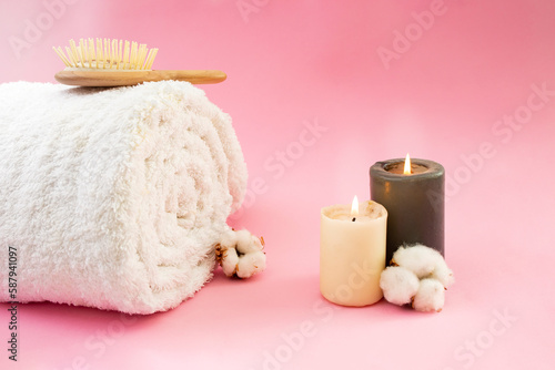 Rolled white towel  wooden hair brush  cotton flowers and lit candles