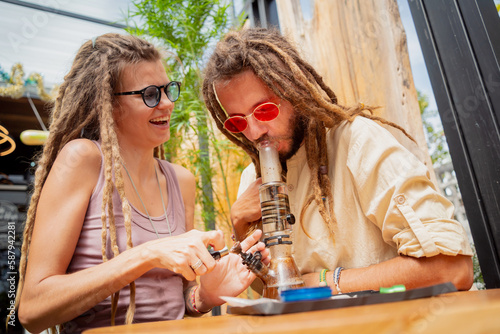 Obraz na plátne Hippie style couple smoking medical marijuana using a bong