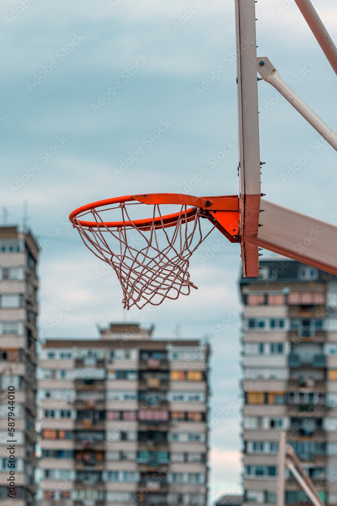 Street hoops, outdoor basketball court rim and the net with apartment building in background