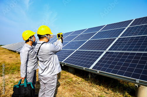 A pair of Asian engineers are inspecting solar photovoltaic power plants outdoors