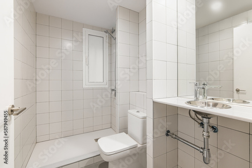 Cozy clean new bathroom with white tiled shower  sink and toilet in a new renovated apartment for a small family. The concept of minimalistic concise design