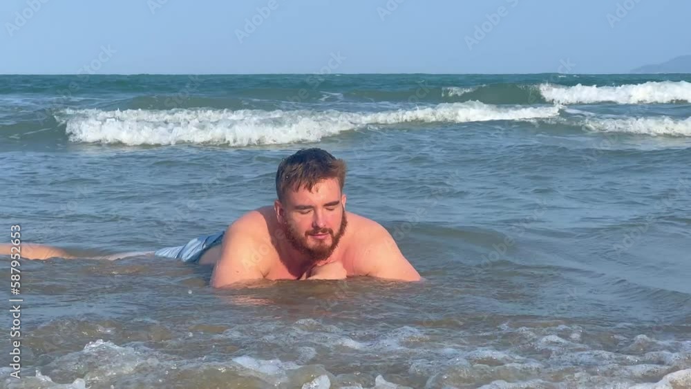 young man smiling in sunny summer weather on the beach and sunbathing young man smiling in sunny summer weather on the beach and sunbathing