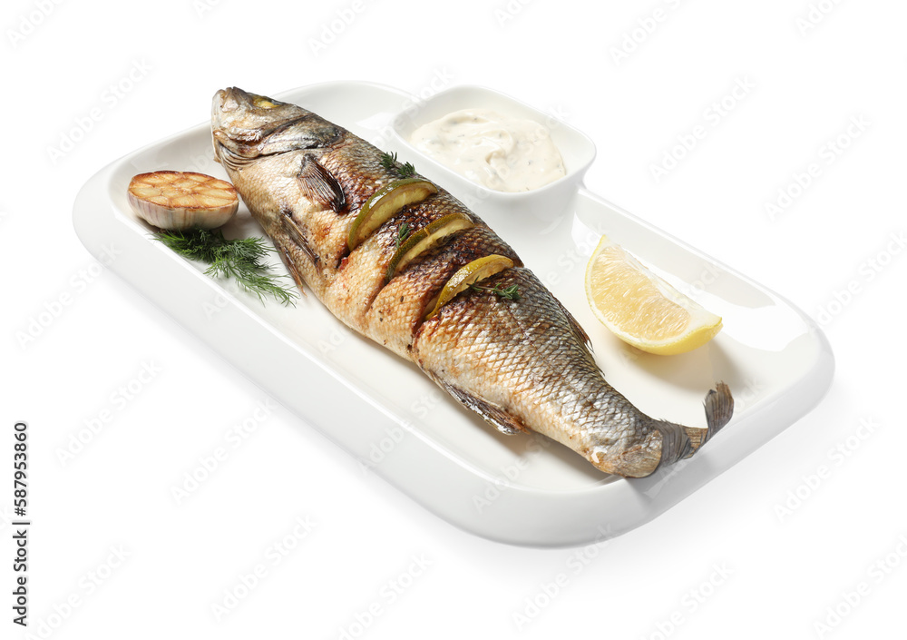 Plate with delicious baked sea bass fish, garlic, slice of lemon and sauce on white background Plate with delicious baked sea bass fish, garlic, slice of lemon and sauce on white background