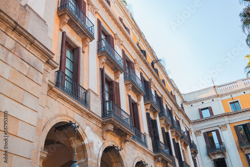 Facade of a typical old Spain residential building in Barcelona, Spain, made of freestone, hosting flats with a architecture and some metal blinders.