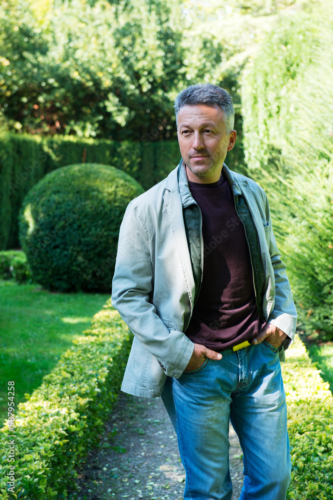 Fototapeta premium Middle-aged man posing in park, summer outdoor portrait. Handsome mature man. Outdoor male portrait.