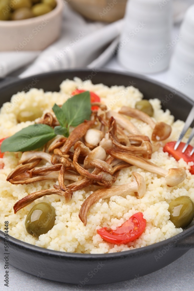 Tasty couscous with mushrooms, olives and tomatoes served on grey table, closeup Tasty couscous with mushrooms, olives and tomatoes served on grey table, closeup