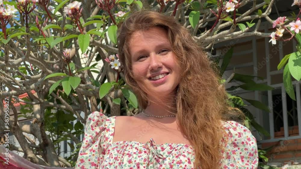 girl smiling against the background of a flowering tree in sunny spring or summer weather girl smiling against the background of a flowering tree in sunny spring or summer weather