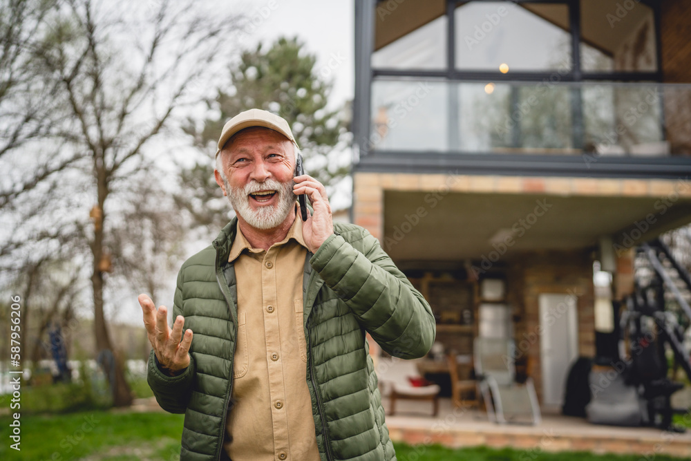 One senior man stand in front of tiny house in day use smart phone One senior man stand in front of tiny house in day use smart phone
