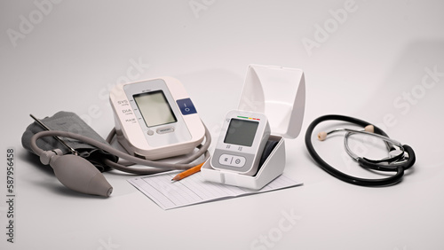 Automatic digital wrist and brachial blood pressure monitor, pressure monitoring chart, pen, stethoscope glasses on white background