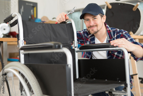 man is repairing a wheelchair at workshop
