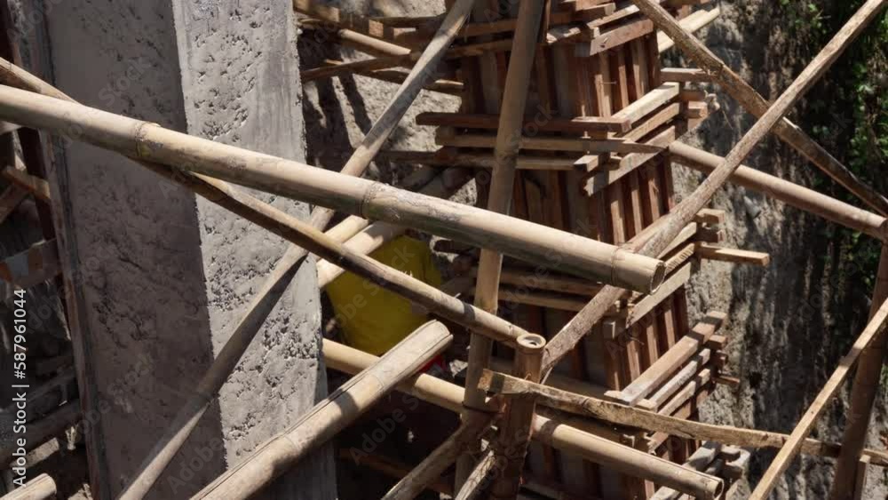 worker-builder of bamboo scaffolding construction site in asia. He works on scaffolding and is wearing a hard hat worker-builder of bamboo scaffolding construction site in asia. He works on scaffolding and is wearing a hard hat