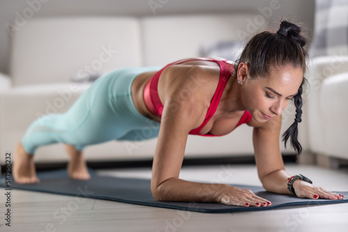 Beautiful fit woman doing a plank on her elbows at home on a mat
