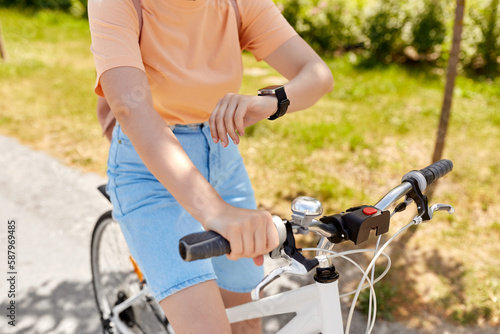 people, leisure and lifestyle - close up of woman with smart watch riding bicycle on city street