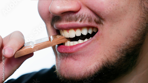 close-up of a man biting milk chocolate