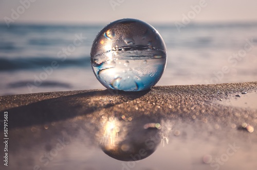 Abstract idea with water with an interesting effect. Glass ball on a blurred background on a seaside beach in Gdynia, Poland. Photo with a shallow depth of field.