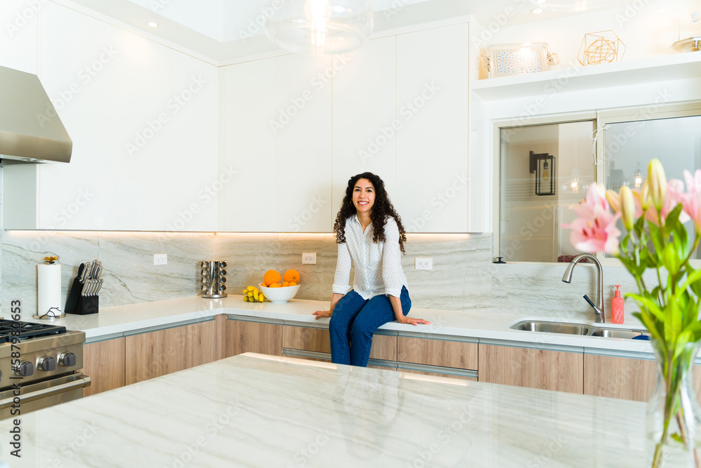 Attractive latin woman sitting in her luxury kitchen Attractive latin woman sitting in her luxury kitchen